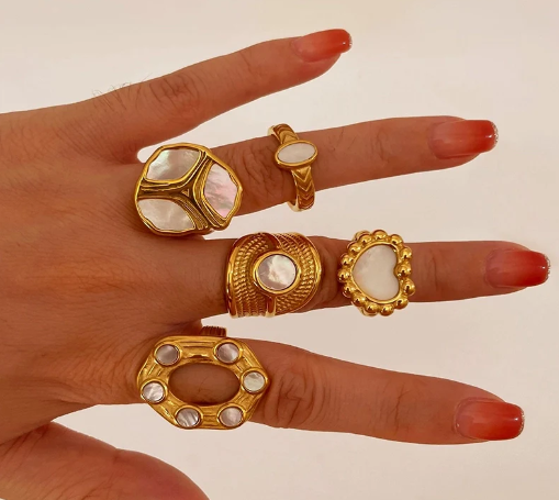 Anillo en forma de corazón con líneas geométricas, usando junto a otros anillos del mismo estilo, todos chapados en oro 18K