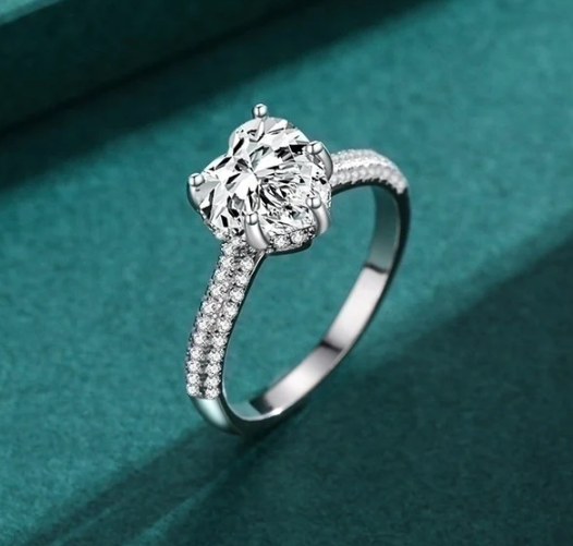 Anillo plata con corazón y circonitas sobre fondo azul de terciopelo, presentación de lujo
