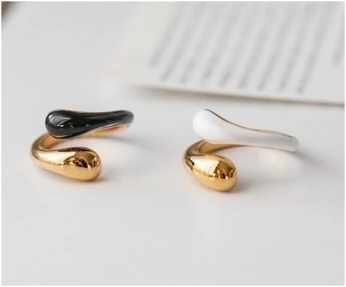 Anillos blanco y negro de acero inoxidable chapados en oro de 18K sobre fondo blanco