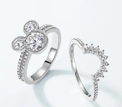 Anillos separados con sombras sobre fondo blanco, diseño geométrico y detalle de corona.