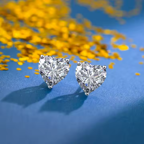 Pendientes corazón en plata de ley con circonita, captando luz directa que realza su brillo y tallado.
