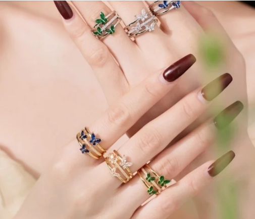 Mano con varios anillos de mariposas en distintos colores, mostrando la variedad de diseños disponibles.