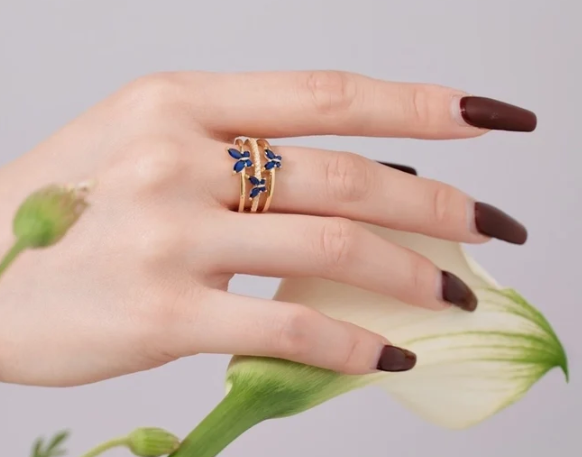 Primer plano del anillo azul y dorado colocado en la mano, destacando la presencia y brillo del diseño en uso