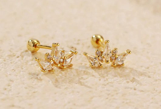 Detalle de los pendientes corona chapados en oro junto a otros accesorios HelloChic@s