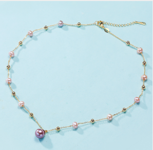 Vista completa del collar Rosé de perlas en tonos rosas y púrpuras sobre fondo gris. Elegancia atemporal.