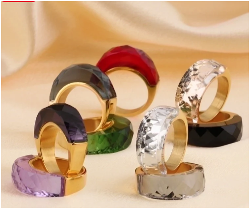 Anillos dorados con piedra de color en composición artística sobre fondo beige