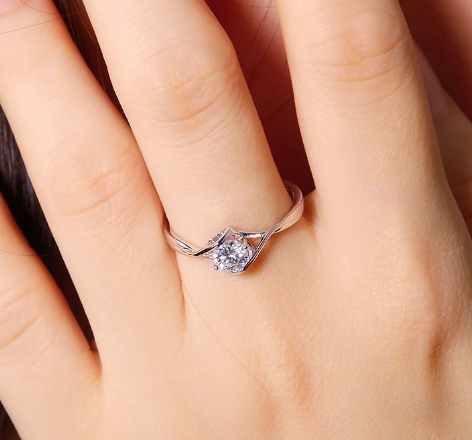 Mano de modelo luciendo anillo solitario de moissanita en forma de corazón en dedo anular