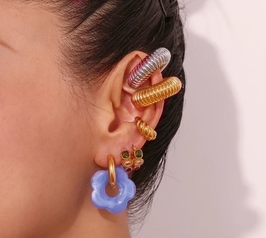 Modelo mostrando los pendientes dorados con detalle en azul, estilo minimalista y fresco