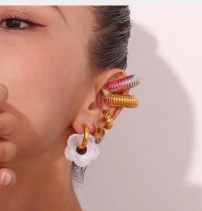 Modelo luciendo pendientes dorados con detalle blanco, elegantes y versátiles