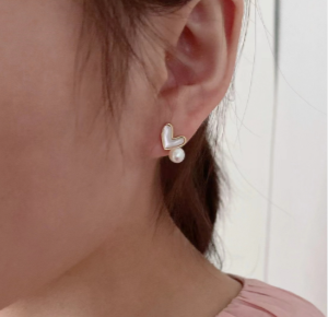 Modelo luciendo pendientes de corazón con perla natural blanca, estilo Hol@perlas