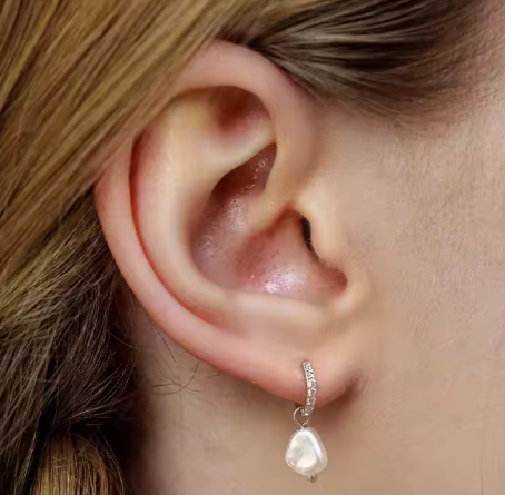 Modelo luciendo pendientes largos con perla natural y acabado en oro 18K