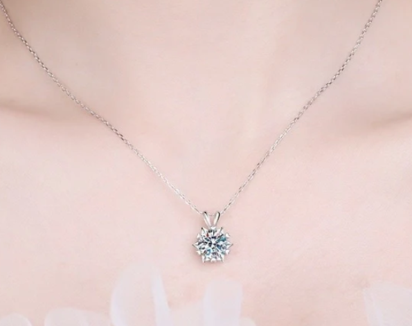 Collar de copo de nieve en plata 925 con moissanita central brillante y halo de zirconitas, captando la luz en fondo neutro