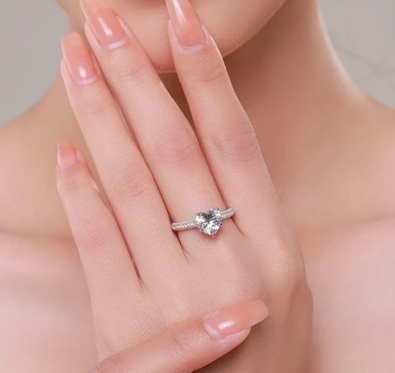 Anillo corazón con circonitas brillantes en mano de modelo, estilo romántico