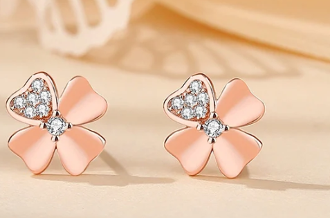 Imagen del pendiente en oro rosa apoyado sobre una superficie de tono rosa beige brillante.