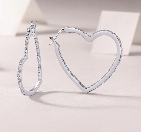 Pendientes de moissanita con forma de corazón sobre fondo gris claro, uno de frente y otro de perfil