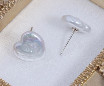 Pendientes botón de perla blanca con forma de corazón sobre fondo blanco