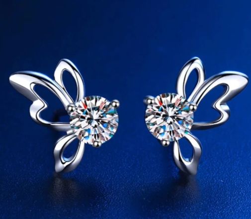 Pendientes mariposa con moissanita iluminados en fondo azul marino suspendidos en aire