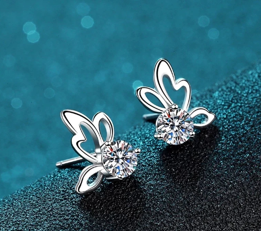 Pendientes mariposa con moissanita vistos de lado con fondo azul desde ángulo izquierdo