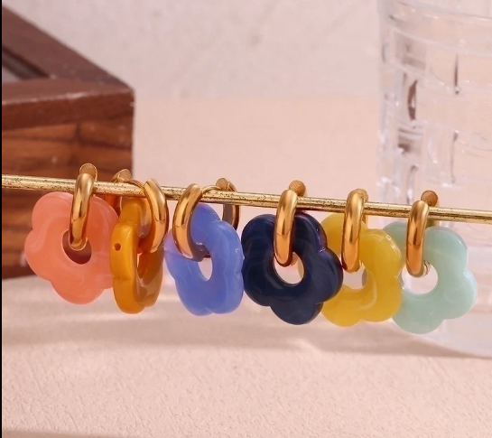 Pendientes dorados minimalistas en varios colores, expuestos sobre una barra metálica