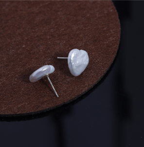 Pendientes en forma de corazón con perlas blancas, estilo elegante sobre fondo negro