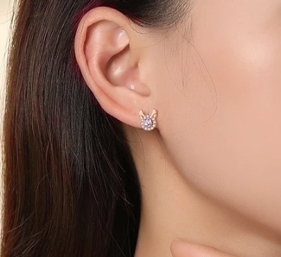 Pendientes de botón Little Dear en oro rosa puestos en la oreja izquierda de la modelo, enfoque lateral.