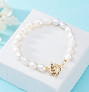 Pulsera elegante de perla barroca con cierre de flor, oro 14K sobre fondo azul
