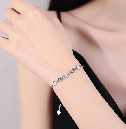 Modelo luciendo pulsera de plata con tréboles y moissanita