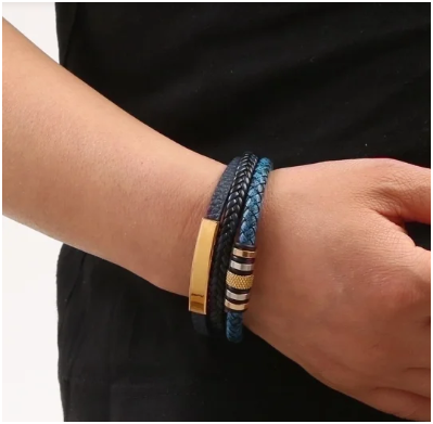 Modelo con camisa negra mostrando pulsera triple de cuero azul con placa dorada central.