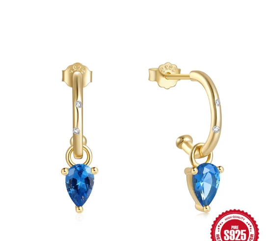 Modelo luciendo los pendientes con movimiento natural del charm azul