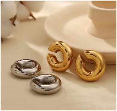 Aros anchos ear cuff en dorado y plateado sobre plato beig, mostrando detalle del chapado en oro 24K y plata, estilo elegante y versátil.
