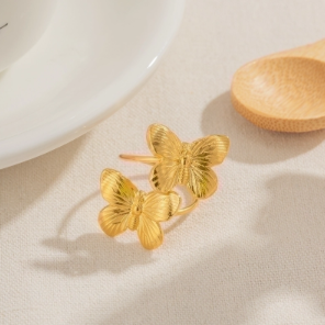 Anillo chapado en oro 18K con dos mariposas sobre fondo blanco, diseño delicado y primaveral