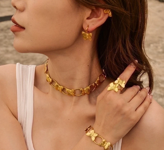 Anillo dorado con mariposas visto desde otro ángulo en la mano de la modelo, joya elegante y simbólica
