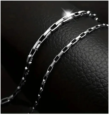 Cadena de botón de acero inoxidable 304 y titanio chapado en plata, colocada sobre joyero negro elegante.