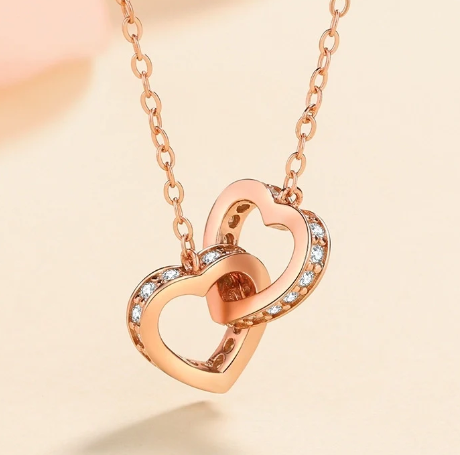 Colgante de moissanita en forma de corazón acabado en oro rosa sobre fondo rosa