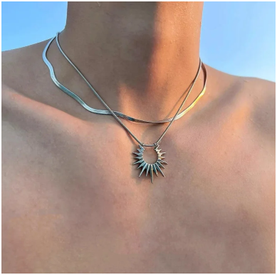 Modelo masculino con el torso descubierto luciendo collar de doble capa en acero de titanio chapado en oro 18K. El diseño queda justo en la clavícula, mostrando cómo resalta el colgante y la caída de las cadenas. Estilo urbano y sofisticado de la colección Hellochic@s-MEN Otoño-Invierno 2025/26.