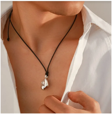 Modelo masculina con camisa blanca abierta mostrando collar minimalista chapado en oro de 18K sobre cuero CCB, fondo blanco.