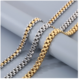 Tres collares de hombre en acero de titanio presentados sobre joyero gris: uno chapado en plata, uno en oro 18K y uno combinado oro-plata. Diseño estilo hip-hop y cierre de mosquetón. Colección Hellochic@s-MEN.