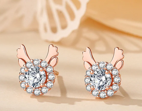 Pendientes botón Little Dear en oro rosa, colocados sobre fondo rosa beige que resalta el brillo cálido del diseño.
