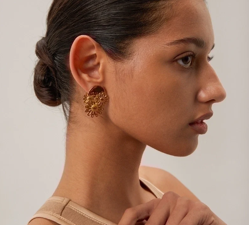 Modelo usando pendientes grandes en forma de flor, chapados en oro 18K, diseño audaz y moderno