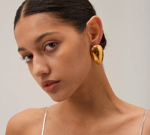 Modelo usando pendientes grandes en forma de gota XL, chapados en oro 18K, estilo audaz y elegante