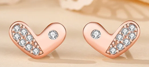 Imagen de los pendientes en oro rosa apoyados en una mesa reflectante color rosa beige.