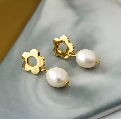 Pendientes flor oro 18k, sobre tela blanca creando ondas, elegante