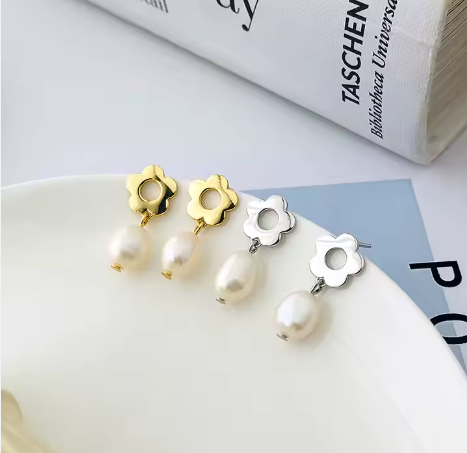 Pendientes flor plata S925 y oro 18k, sobre plato blanco, revista