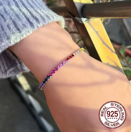  Modelo mostrando la pulsera tenis multicolor de plata de ley 925 en la mano izquierda