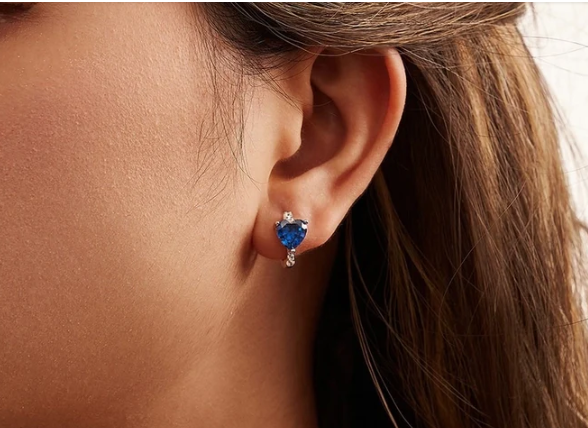 Detalle de pendiente en forma de corazón azul con brillo de circonitas