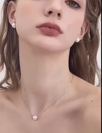 Video mostrando pendientes de perla natural tipo botón en tonos blanco, polvo naranja y morado claro, destacando su elegancia atemporal y versatilidad.