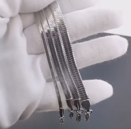 Vídeo de joyero con guantes blancos mostrando cadenas de hombre en acero de titanio chapado en plata. Se aprecian distintos grosores y texturas, reforzando la resistencia y acabado premium de la colección Hellochic@s-MEN.