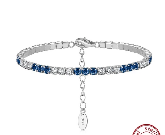 Video mostrando la pulsera tipo tenis en plata S925 con circonitas blancas y azules de 3 mm girando lentamente sobre fondo blanco, destacando su brillo y acabado pulido.