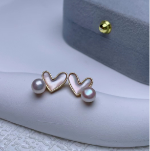 Video mostrando pendientes de corazón con perla natural de agua dulce y acabado blanco cerado, destacando su diseño ligero y elegante.