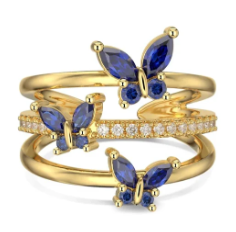 Anillo de mariposas en azul y dorado girando lentamente sobre fondo neutro, mostrando el brillo de la zirconita central y el esmaltado en detalle.